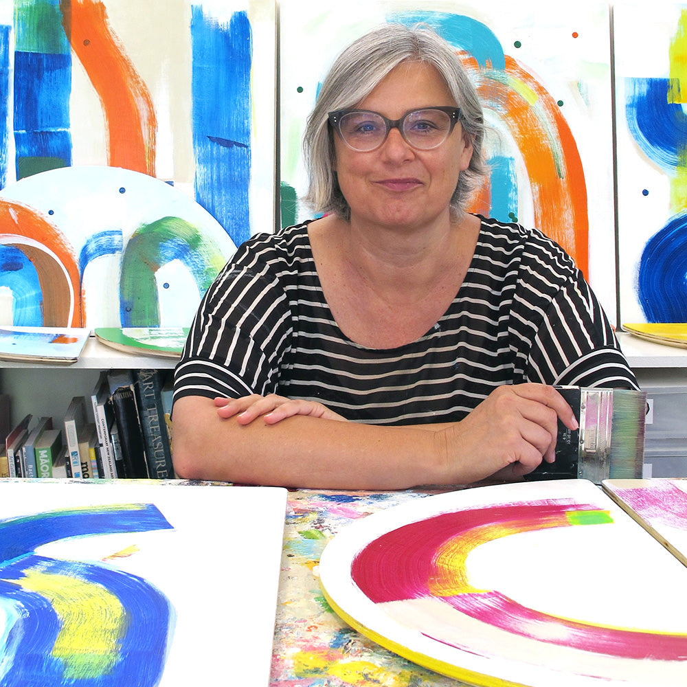 Photo of Kirsty Black in her art studio surrounded by her abstract artworks in progress